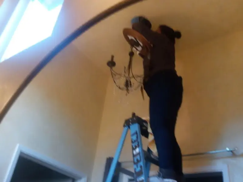 Electrician installing a chandelier in a Shenango residence